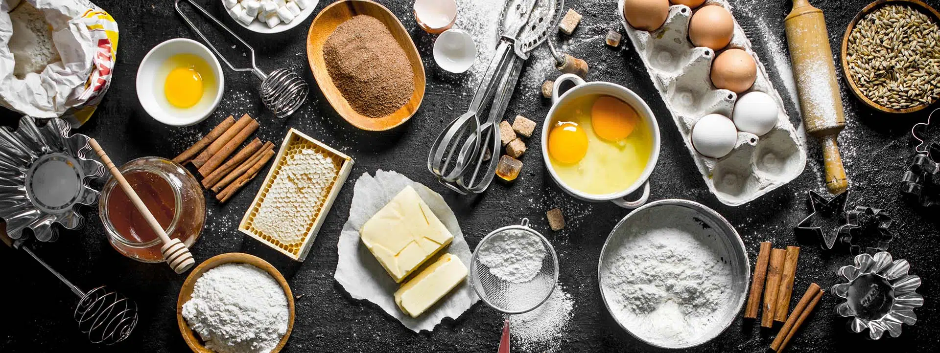 CBD Baking ingredients, egg, flour, butter etc on a black work surface